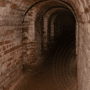 Couloir d’un ancien bunker en briques, voûté et souterrain, illustrant la transformation de structures militaires en centres de données ultra-sécurisés. L’architecture robuste et l’absence de lumière naturelle soulignent l’intérêt stratégique de ces lieux pour l’hébergement numérique. Logo « dcod » en bas à droite.