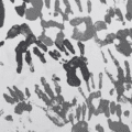 Mur recouvert de multiples empreintes de mains d'enfants peintes en différentes nuances de gris, créant un motif artistique abstrait. Logo « dcod » visible en bas à droite.