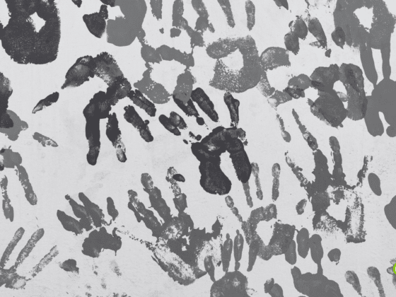 Mur recouvert de multiples empreintes de mains d'enfants peintes en différentes nuances de gris, créant un motif artistique abstrait. Logo « dcod » visible en bas à droite.