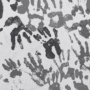 Mur recouvert de multiples empreintes de mains d'enfants peintes en différentes nuances de gris, créant un motif artistique abstrait. Logo « dcod » visible en bas à droite.
