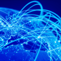 Carte du monde en teintes bleues avec des lignes lumineuses symbolisant les connexions Internet et les échanges de données à l’échelle mondiale.