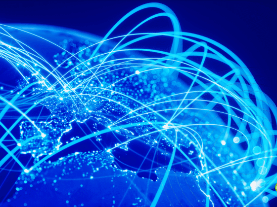 Carte du monde en teintes bleues avec des lignes lumineuses symbolisant les connexions Internet et les échanges de données à l’échelle mondiale.