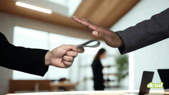 Main d’un homme en costume refusant une liasse de billets tendue par une autre personne, symbolisant le rejet de la corruption en entreprise. Scène dans un bureau moderne, avec le logo "dcod" en bas à droite.