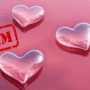 Image de trois cœurs roses en verre sur fond rose, avec le mot « SCAM » en rouge, illustrant les arnaques amoureuses sur Internet.