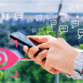 Personne utilisant un smartphone avec des bulles de messages et une icône d’œil rose, symbolisant la surveillance des échanges numériques et les enjeux de confidentialité sur mobile.