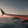 Photographie prise depuis le hublot d’un avion WestJet en vol, montrant une aile d’avion survolant une mer de nuages au coucher du soleil, avec le logo "dcod" en bas à droite.