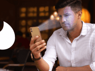Tinder impose la vérification faciale pour lutter contre les faux profils et les arnaques 7 Un homme utilise la reconnaissance faciale sur son smartphone pour se connecter à une application de rencontre, avec le logo de Tinder visible à gauche de l’image. Un motif numérique est superposé sur son visage pour illustrer le processus de vérification biométrique.