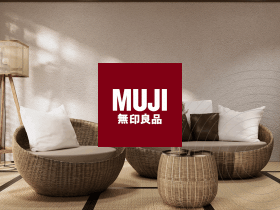 Salon au style japonais épuré avec fauteuils ronds en rotin, lampadaire en bois, tatami au sol et logo MUJI au centre, illustrant l’esthétique minimaliste et naturelle de la marque.