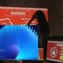 Une femme observe un écran rouge affichant un message de ransomware, entourée d’ordinateurs compromis, avec en surimpression la couverture du rapport « Microsoft Digital Defense Report 2025 » sur la cybersécurité.