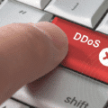 Gros plan sur un doigt appuyant sur une touche rouge marquée « DDoS », symbolisant l’initiation d’une attaque par déni de service distribué.