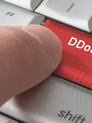 Gros plan sur un doigt appuyant sur une touche rouge marquée « DDoS », symbolisant l’initiation d’une attaque par déni de service distribué.