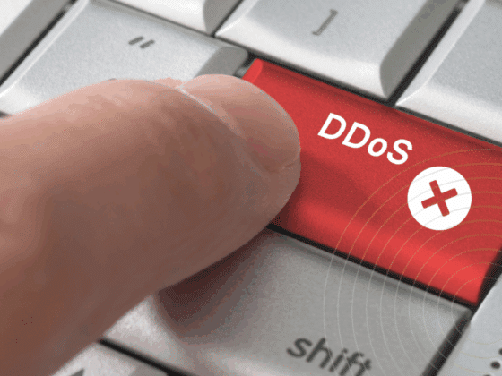 Gros plan sur un doigt appuyant sur une touche rouge marquée « DDoS », symbolisant l’initiation d’une attaque par déni de service distribué.