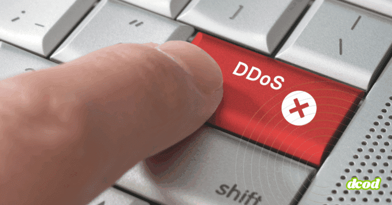 Gros plan sur un doigt appuyant sur une touche rouge marquée « DDoS », symbolisant l’initiation d’une attaque par déni de service distribué.