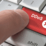 Gros plan sur un doigt appuyant sur une touche rouge marquée « DDoS », symbolisant l’initiation d’une attaque par déni de service distribué.