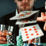 Homme en costume jetant ses cartes lors d'une partie de poker, avec des piles de jetons colorés et un verre de whisky à la main, illustrant l’intensité et le suspense du jeu.