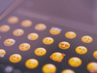 Gros plan sur l’écran d’un smartphone affichant une sélection d’émojis souriants, symbolisant l’expression des émotions dans la communication numérique via messagerie instantanée ou réseaux sociaux.