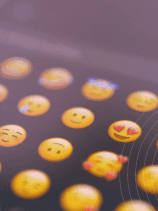 Gros plan sur l’écran d’un smartphone affichant une sélection d’émojis souriants, symbolisant l’expression des émotions dans la communication numérique via messagerie instantanée ou réseaux sociaux.