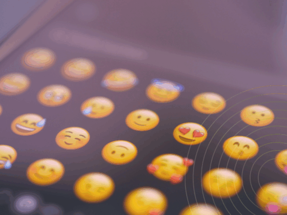 Gros plan sur l’écran d’un smartphone affichant une sélection d’émojis souriants, symbolisant l’expression des émotions dans la communication numérique via messagerie instantanée ou réseaux sociaux.