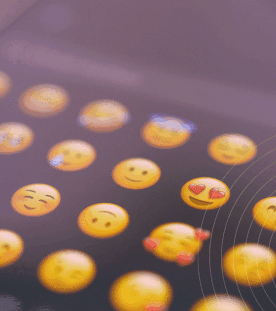 Gros plan sur l’écran d’un smartphone affichant une sélection d’émojis souriants, symbolisant l’expression des émotions dans la communication numérique via messagerie instantanée ou réseaux sociaux.