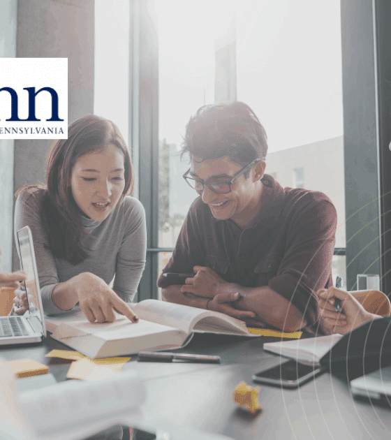 Groupe d’étudiants en pleine séance de travail collaboratif autour d’une table, avec ordinateurs portables et livres, dans une salle lumineuse de l’Université de Pennsylvanie (Penn), logo visible à l’arrière-plan.
