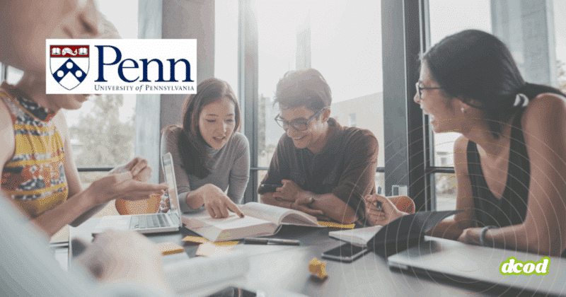 Groupe d’étudiants en pleine séance de travail collaboratif autour d’une table, avec ordinateurs portables et livres, dans une salle lumineuse de l’Université de Pennsylvanie (Penn), logo visible à l’arrière-plan.