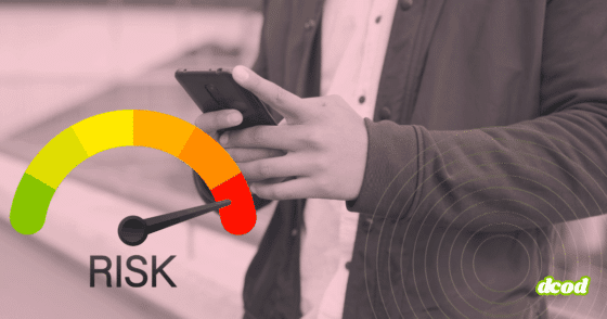 Personne tenant un smartphone entre les mains, vue cadrée au niveau du buste sans montrer le visage. À gauche, un cadran de risque en couleurs allant du vert au rouge affiche une aiguille pointant vers la zone de danger. À droite, des cercles concentriques évoquent une détection ou une analyse du signal. Le logo « dcod » apparaît en bas à droite.