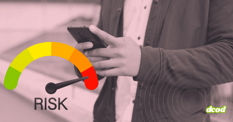 Personne tenant un smartphone entre les mains, vue cadrée au niveau du buste sans montrer le visage. À gauche, un cadran de risque en couleurs allant du vert au rouge affiche une aiguille pointant vers la zone de danger. À droite, des cercles concentriques évoquent une détection ou une analyse du signal. Le logo « dcod » apparaît en bas à droite.