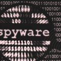 Image montrant le mot « spyware » agrandi au centre d’un fond composé de lignes de code en binaire floues, évoquant une surveillance numérique et l’analyse de données. Un motif circulaire rappelle une cible ou un radar, avec un logo « dcod » en bas à droite.