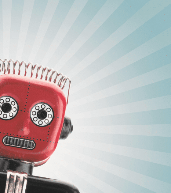 Petit robot rouge au style vintage, incliné vers la gauche, sur fond bleu clair avec des rayons lumineux stylisés.