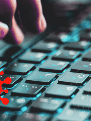 Gros plan sur une main tapant sur un clavier d’ordinateur, avec en surimpression une icône rouge représentant un virus informatique menaçant.