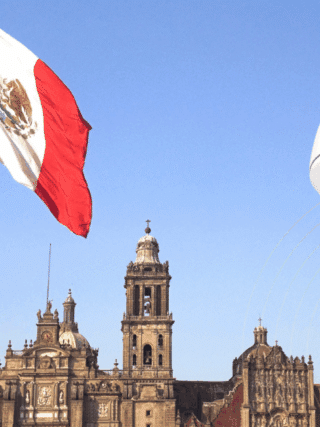 Grand drapeau mexicain flottant devant la cathédrale métropolitaine de Mexico, avec en premier plan une caméra de vidéosurveillance moderne illustrant l’essor des technologies de sécurité dans l’espace public.