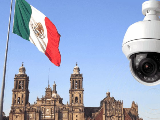 Grand drapeau mexicain flottant devant la cathédrale métropolitaine de Mexico, avec en premier plan une caméra de vidéosurveillance moderne illustrant l’essor des technologies de sécurité dans l’espace public.