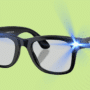 Paire de lunettes noires au style classique projetant des faisceaux lumineux bleus depuis les coins supérieurs, sur fond vert clair, évoquant une technologie avancée ou un effet visuel humoristique.