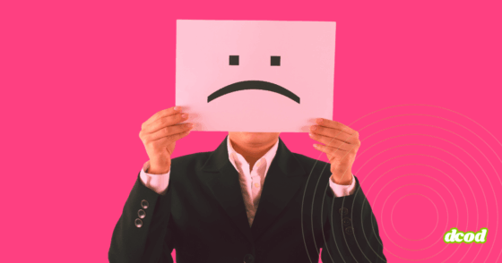 Une personne en costume tenant devant son visage une feuille avec un visage triste, symbolisant une potentielle menace interne en entreprise.