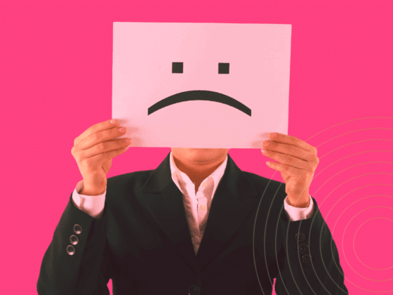 Une personne en costume tenant devant son visage une feuille avec un visage triste, symbolisant une potentielle menace interne en entreprise.