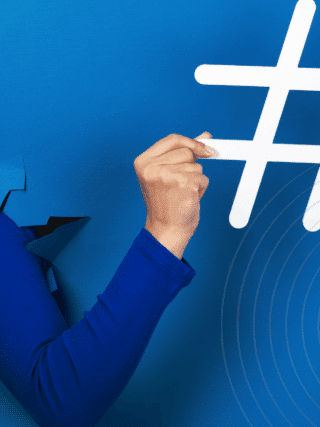 Bras sortant d’une déchirure dans un mur bleu vif, tenant un grand symbole de hashtag blanc, illustrant le pouvoir des réseaux sociaux et des tendances numériques.