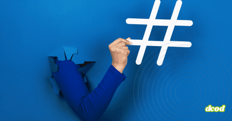 Bras sortant d’une déchirure dans un mur bleu vif, tenant un grand symbole de hashtag blanc, illustrant le pouvoir des réseaux sociaux et des tendances numériques.