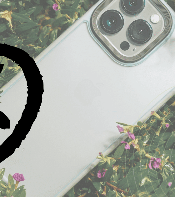 Un smartphone clair partiellement entouré de plantes, recouvert d’un large symbole noir en forme de cercle barré.