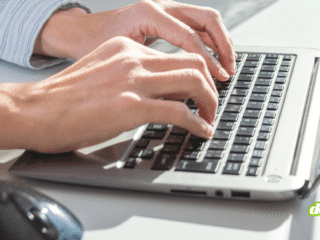 Gros plan sur des mains utilisant un ordinateur portable sur un bureau, illustrant un usage professionnel quotidien et la dépendance croissante au poste de travail numérique.