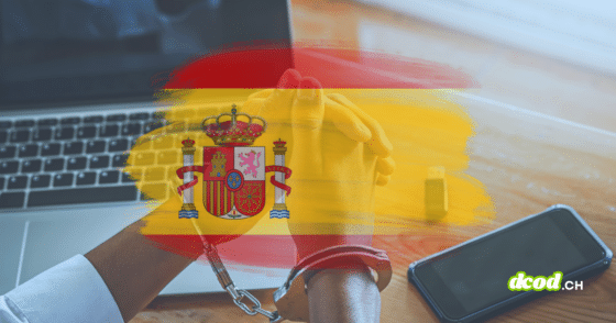 Mains menottées devant un ordinateur portable, avec drapeau espagnol en surimpression et smartphone sur la table.