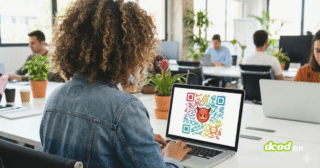 Une femme de dos à un bureau tape sur un ordinateur portable. L'écran affiche un grand QR code multicolore avec un emoji diable rouge au centre, illustrant un lien malveillant.