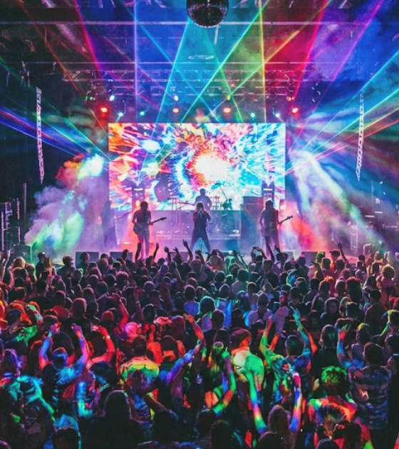 Foule dansant lors d'un concert animé, la scène et les murs étant éclairés par des projections lumineuses psychédéliques et des faisceaux laser de toutes les couleurs. Une illustration aussi associée aux risques des billetteries des faux billets