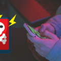 Une personne tient un smartphone tandis qu’un pictogramme de tête de mort signale une alerte de malware mobile.