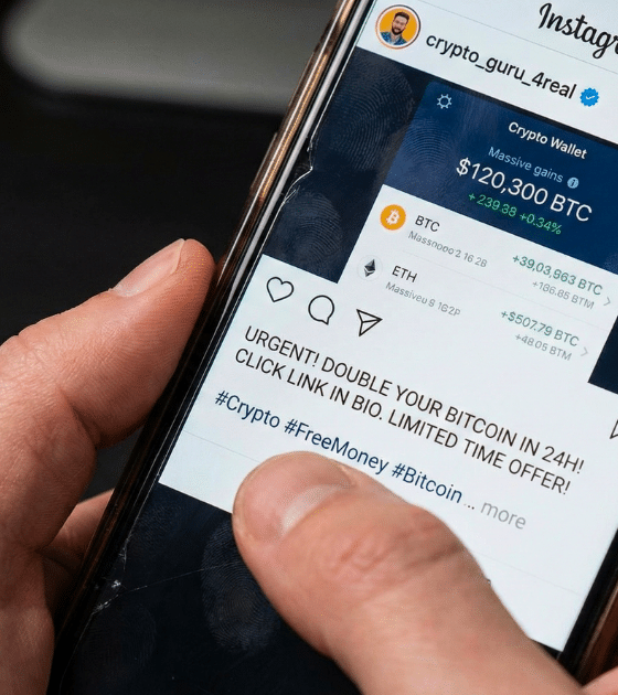 Gros plan sur des mains tenant un smartphone, montrant un doigt sur une publication Instagram frauduleuse promettant de "doubler vos Bitcoin". Le compte "crypto_guru_4real" tente d'attirer des victimes via un lien malveillant, illustrant une méthode de piratage Instagram et d'arnaque aux cryptomonnaies.