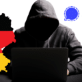 Illustration montrant un hacker encapuchonné devant un ordinateur, entouré de la carte de l'Allemagne aux couleurs du drapeau et du logo de l'application Signal.