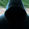 Gros plan en contre-plongée sur la silhouette sombre et sans visage d'un individu portant une capuche. Le tissu vert, blanc et rouge du drapeau iranien est visible à travers l'ouverture de la capuche. Le logo DCOD est situé en bas à droite de l'image.