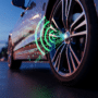 hotographie d'une roue de voiture moderne dont la valve de pneu émet des ondes radio et des données numériques lumineuses, symbolisant la transmission sans fil d'un capteur de pression des pneus TPMS en milieu urbain.