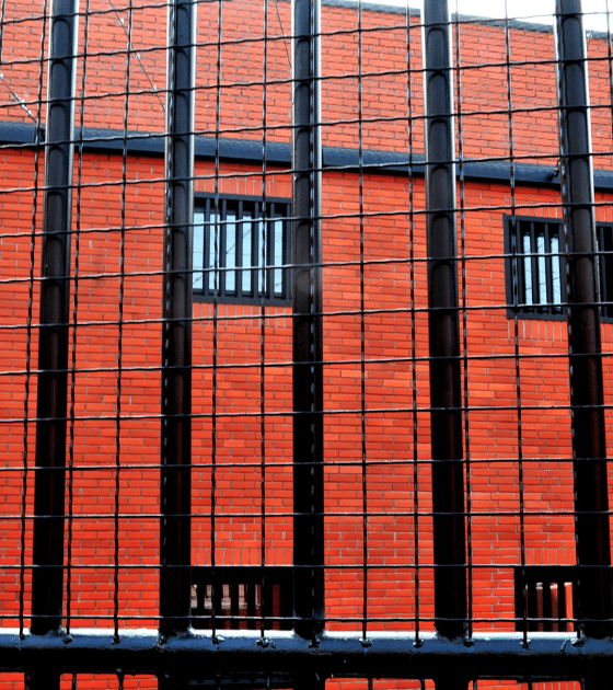 Illustration de l'incarcération injuste : vue de barreaux de prison sur fond de mur en briques rouges, évoquant les conséquences d'une erreur de reconnaissance faciale.