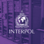 Illustration d'une salle de serveurs informatiques avec le logo d'Interpol en blanc sur un filtre violet, symbolisant le démantèlement d'infrastructures cybercriminelles lors de l'opération Synergia III.
