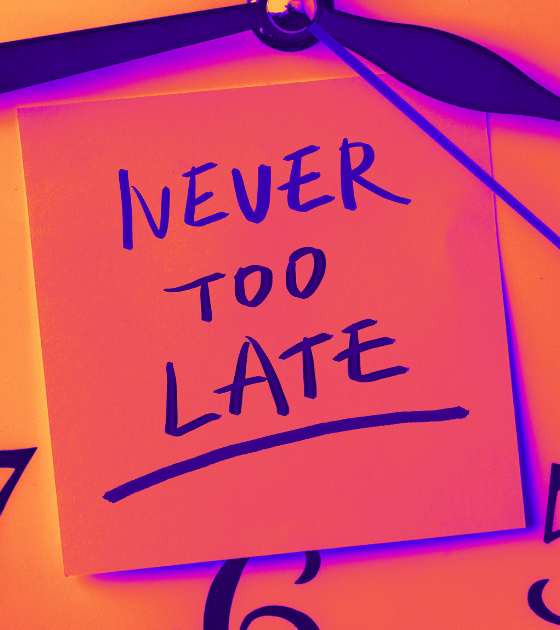 Image d'illustration sur l'urgence cyber : Gros plan en tons chauds sur un cadran d'horloge. Au centre, une note adhésive porte l'inscription manuscrite "NEVER TOO LATE", soulignant la nécessité pour le NIST de trier les vulnérabilités pour éviter le chaos. Le logo DCOD.ch est visible dans le coin inférieur droit.